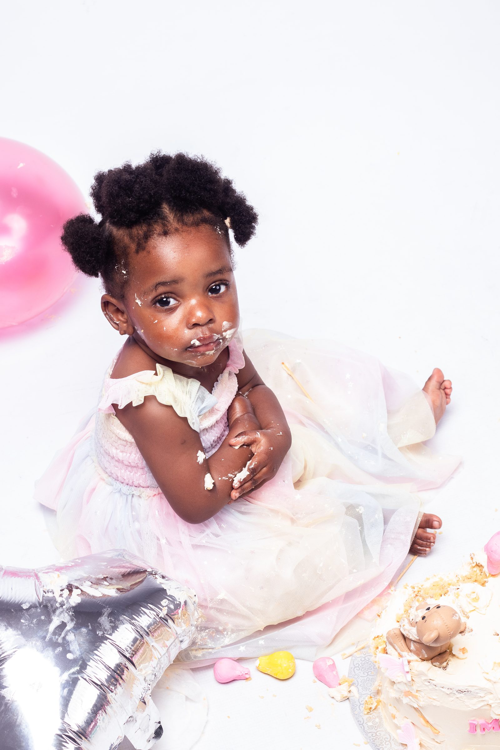 A toddler at her first birthday cake smash